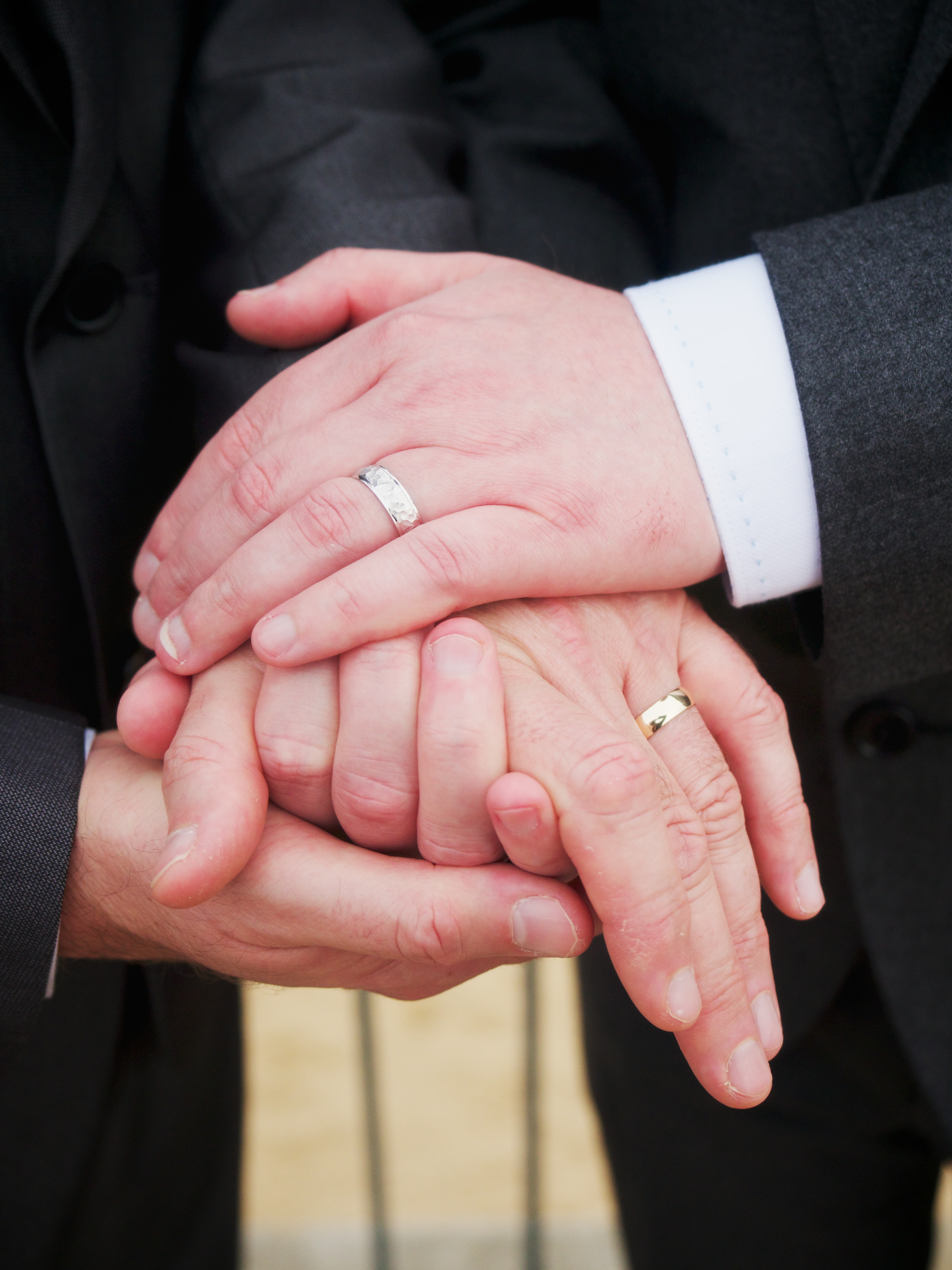 Two men holding hands with wedding rings