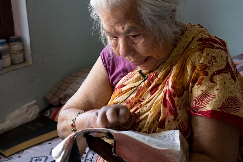 A leprosy victim in Nepal reads the Bible.